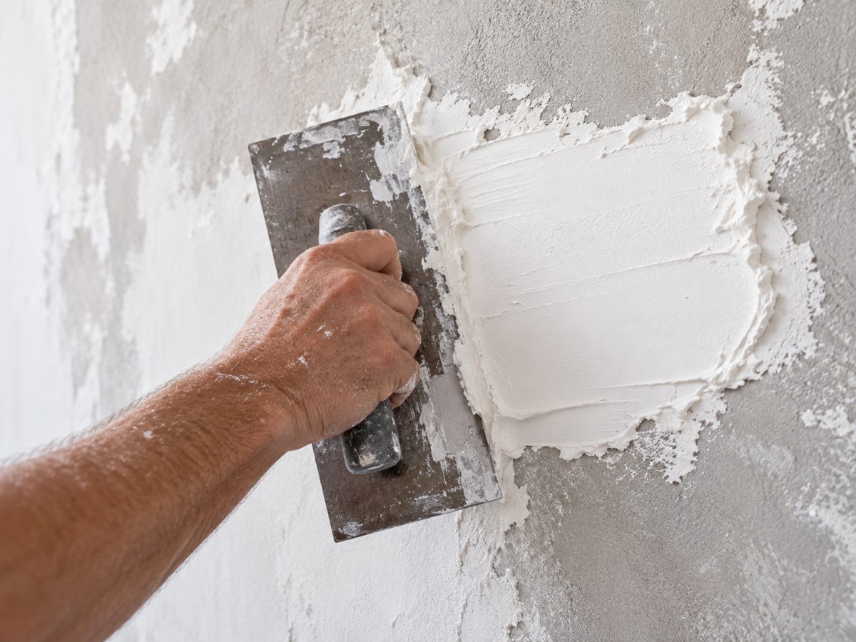 Handwerker trägt mit der Glättkelle frischen Putz auf eine Wand auf