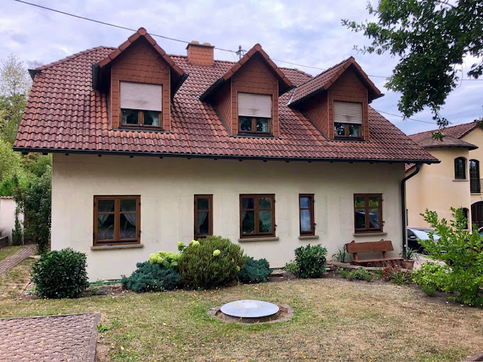 Einfamilienhaus mit cremefarbener Fassade und roten Dachgauben