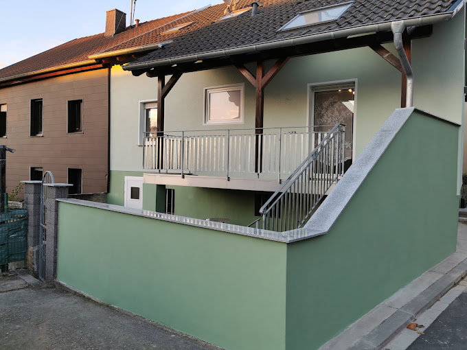 Wohnhaus mit grüner Fassade, Außentreppe und Balkon