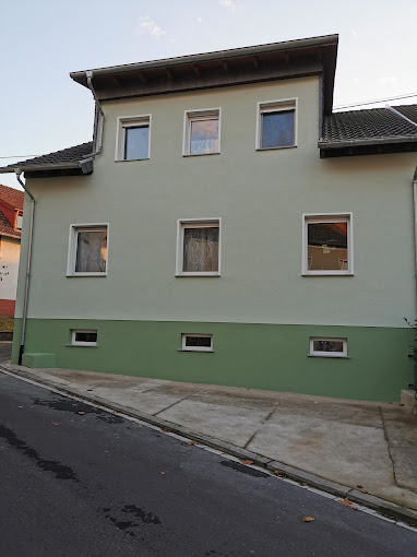 Mehrfamilienhaus mit hellgrüner Fassade und dunkelgrünem Sockel