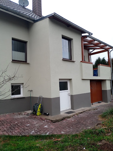 Fassade in Cremeweiß mit grauem Sockel nach der Sanierung