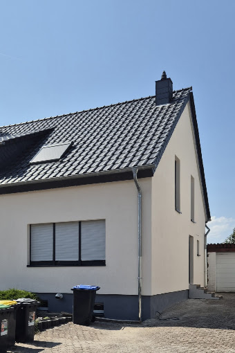 Frisch gestrichene, helle Giebelfassade mit grauem Sockel