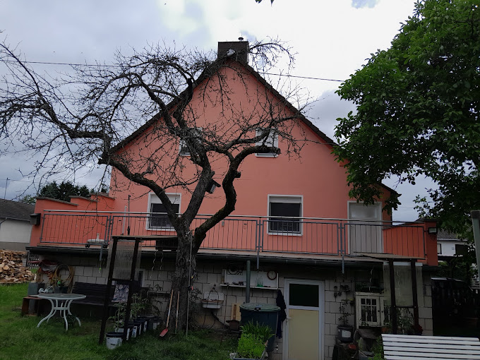 Haus mit lachsfarbener Fassade und Balkon im Garten