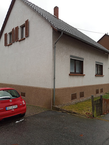 Giebelhaus mit weißer Fassade und braunem Sockel